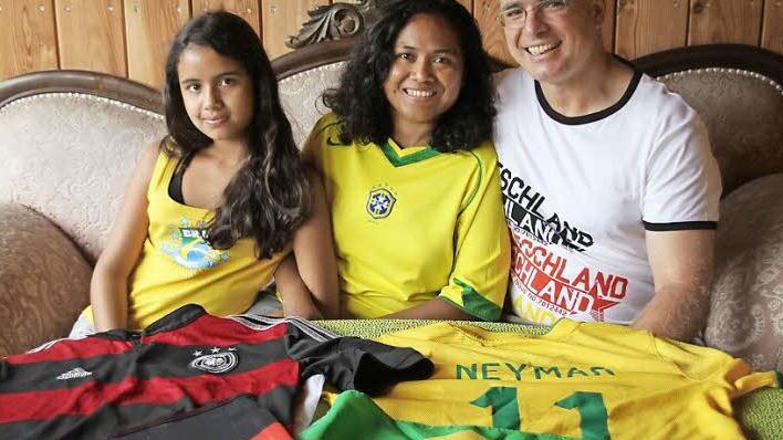 Deutschland- und Neymar-Trikot wie die Fahnen beider Heimatländer liegen bereit: Iris, Valdinez und Oliver Dünisch (von links) stehen für deutsch-brasilianische Freundschaft, aber auch fußballerische Konkurrenz.