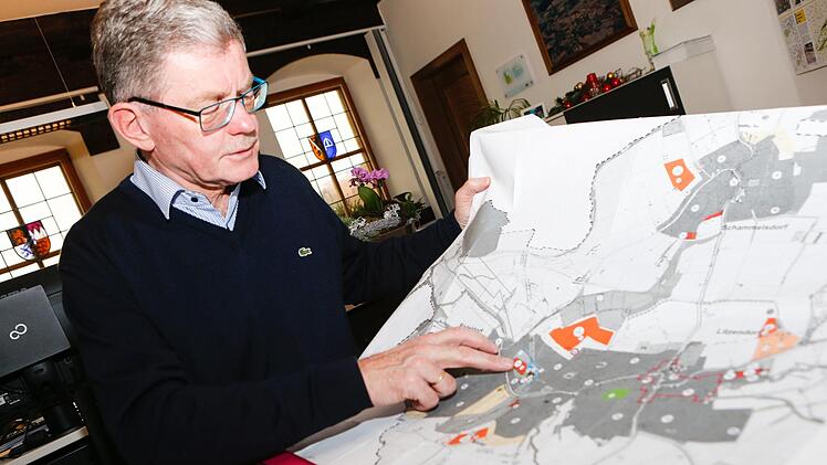 Bürgermeister Wolfgang Möhrlein zeigt auf einem Flächennutzungsplan, welche ursprünglich geplanten Baugebiete der Ortsteile Litzendorf, Naisa und Pödeldorf wieder gestrichen wurden. Stattdessen setzt die Gemeinde auf Innenentwicklung. Foto: Matthias Hoch
