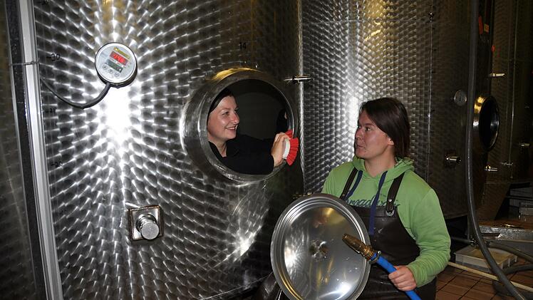 Auszubildende Kathrin Ritzel (links) und Winzerin Sonja Sehm bereiten im Lager des Ramsthaler Weinguts Baldauf die Edelstahl-Tanks für die neue Ernte vor.