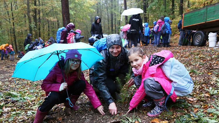 Melina und Mia pflanzen mit Försterin Rita Satzger  einen Baum.