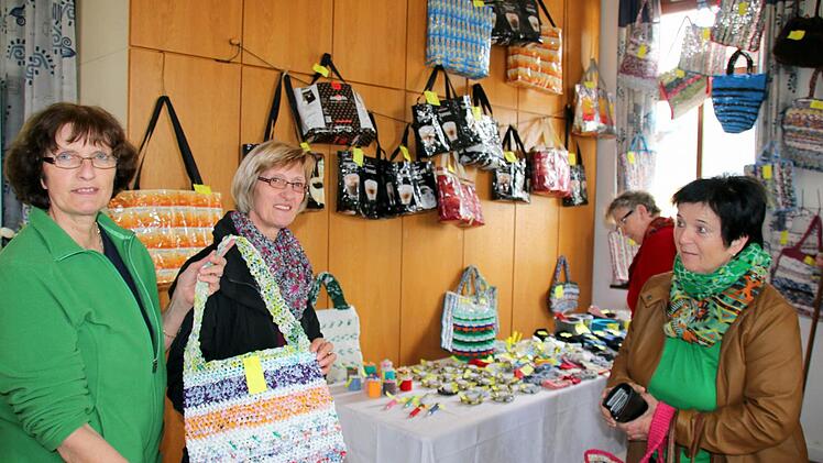 Ein Zeichen gegen zu zunehmende Vermüllung möchten die Damen der Gemünner Lichtstube setzen. Barbara Hämmelmann (links) hatte die Idee einfache Plastiktüten zu kunstvollen Einkaufstaschen zu verarbeiten und setzte sie zusammen mit den Frauen der Lichtstube, zu der auch Doris Dürr (Mitte) gehört. Beim Basar im Gemeindehaus fanden die Taschen schnell Anklang. Christine Schippel (rechts) erstand eine der ersten Kunstwerke. Foto: Bettina Knauth