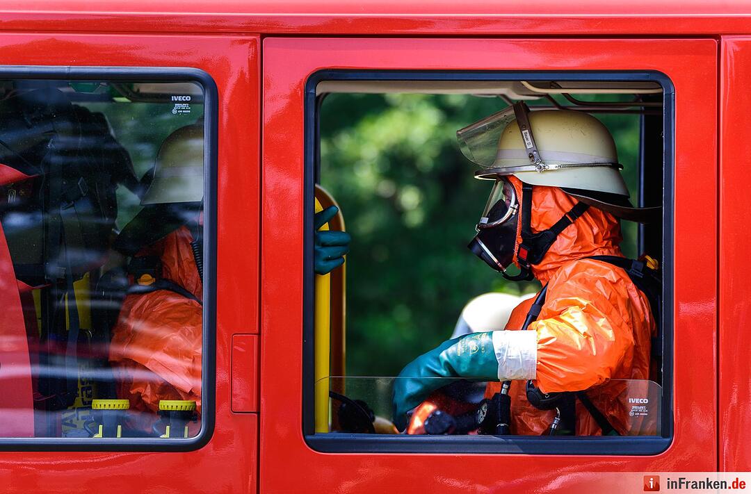 Einsatzkräfte der Feuerwehr mit Ganzkörper-Schutzanzügen sitzen am 11.08.2015 in Engelmannsreuth (Bayern) in einem Einsatzfahrzeug. Bei Engelmannsreuth ist ein F-16 Kampfjet der US-Streitkräfte abgestürzt. Foto: Nicolas Armer/dpa