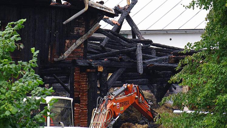 Der Bagger der Gemeinde entfernt die verkohlten Balken, damit die Feuerwehrkräfte zu den restlichen Glutnestern vordringen können.