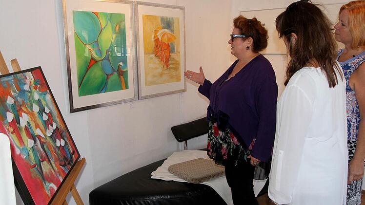 Ausstellungsleiterin und Kunstdozentin Gabriele Schöpplein (links) mit Besuchern vor einigen der Bilder, die von einer Vietnam-Reise inspiriert worden waren.