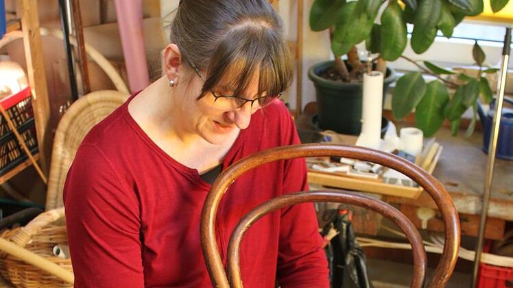 Iris Schneider beim Reparieren eines klassischen Bistrostuhls in ihrer Werkstatt