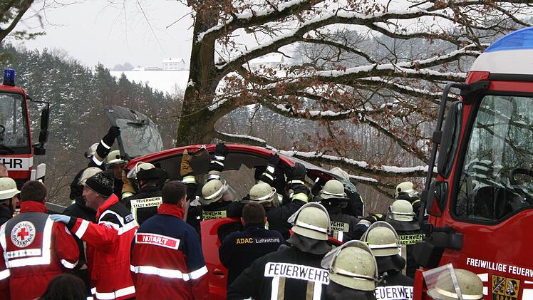 Feuerwehrleute heben das Dach des Kleinwagens an.