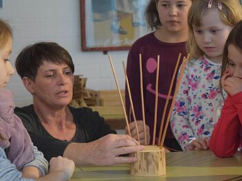 Gitti Klitzner erklärt den Kindern, wie der Thron geflochten werden muss. Foto: Daniela Pondelicek