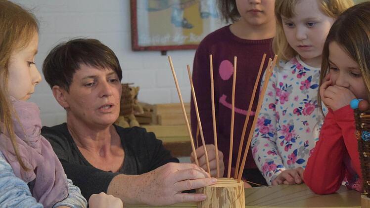 Gitti Klitzner erklärt den Kindern, wie der Thron geflochten werden muss. Foto: Daniela Pondelicek