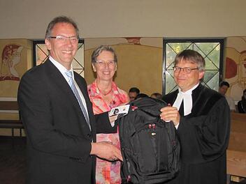 Bürgermeister Thomas Nowak und Monika Biederer, beide vom Kirchenvorstand, gaben Pfarrer Ulrich Willmer einen voll gepackten Rucksack mit auf den Weg nach Nürnberg. Zum Marschproviant gehörten auch Coburger Bratwürste. Foto: Martin Koch