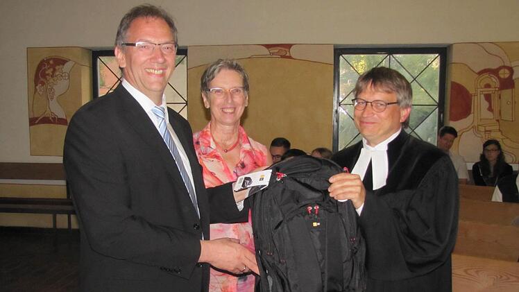 Bürgermeister Thomas Nowak und Monika Biederer, beide vom Kirchenvorstand, gaben Pfarrer Ulrich Willmer einen voll gepackten Rucksack mit auf den Weg nach Nürnberg. Zum Marschproviant gehörten auch Coburger Bratwürste. Foto: Martin Koch