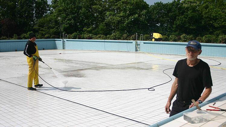 Für letzte Arbeiten Spachtel, Hand und Schlauch angelegt: die Bademeister Heinz Zürl und Klaus Hanke (vorne) im Kinderbecken.Fotos: Ralf Kestel