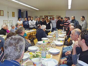 Die Bramberger Bürger nahmen Platz und die Asylbewerber erwiesen sich als sehr gute Gastgeber und Köche. Siza Saby (hinten in der Mitte stehend) erklärte den Gästen die Zubereitung der Speisen aus dem Irak und Syrien. Foto: Johanna Eckert
