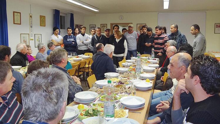 Die Bramberger Bürger nahmen Platz und die Asylbewerber erwiesen sich als sehr gute Gastgeber und Köche. Siza Saby (hinten in der Mitte stehend) erklärte den Gästen die Zubereitung der Speisen aus dem Irak und Syrien. Foto: Johanna Eckert