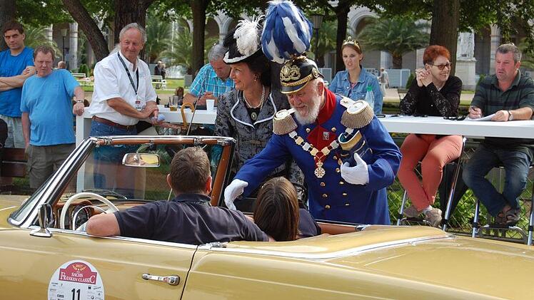 Prinzregent Luitpold (Peter Krug) in der blauen Uniform und Kaiserin Auguste Victoria (Karin Matthes, daneben) begrüßen die Fahrer beim Concour d'Elegance, dahinter die Jury. Foto: Sigismund von Dobschütz