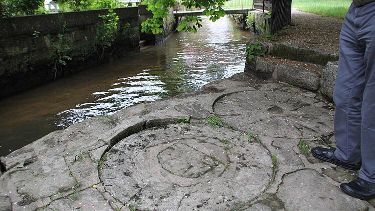 Alte Mühlsteine sind ins Pflaster des schmalen Fußwegs am Rande des Mühlbachs eingelassen. Sie erinnern an die Geschichte der Mühle. Foto: Ulrike Müller