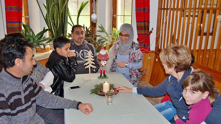 Helferin Hilde Venohr mit der kleinen Amila (8) im Arm spricht mit (von links) Vadel (34) aus Syrien, seinem Sohn Danir (11) sowie dem irakischen Ehepaar Hussein (39) und Faten (36).  Foto: Sigismund von Dobschütz