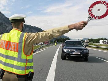 Ein Polizist winkt ein Auto für eine Fahrzeugkontrolle von der Straße.Bild: dpa