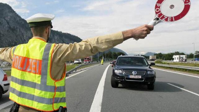 Ein Polizist winkt ein Auto für eine Fahrzeugkontrolle von der Straße.Bild: dpa