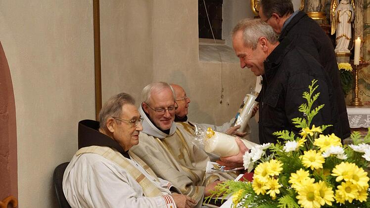 Kirchenpfleger Erich Marx (rechts) schenkt Pater Bonaventura (links) eine Kerze mit Abbildungen der Kirchen von Morlesau und Ochsenthal sowie einen Kalender. Pater Dagobert bekommt von Kirchenpfleger Hans-Peter Hergenröther das gleiche Andenken. Fotos: Guzy