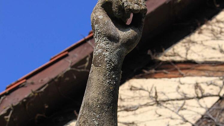 Der rechte, erhobene, Arm der Figur weist mit die stärksten Schäden auf. So sieht er mittlerweile, dank Absplitterungen und Flechten-Bewuchs, fast schon wie ein verrottender Ast aus. Foto: Katharina Brecht