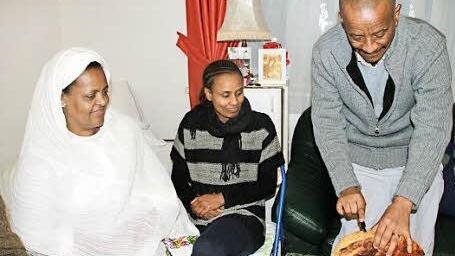 Der älteste Mann im Raum schneidet das Weihnachtsbrot an.