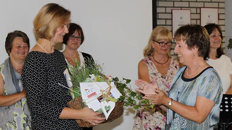 Christine Weininger überreicht Sigrid Schumm (r.) einen Präsentkorb. Dahinter stehen die Kolleginnen vom Lehrerchor. Foto: Carmen Schwind