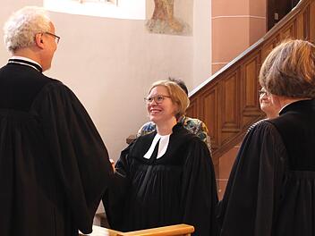 Dekan Hans-Martin Lechner übergibt Pfarrerin Kathrin Seeliger die Urkunde.   Foto: Evi Seeger