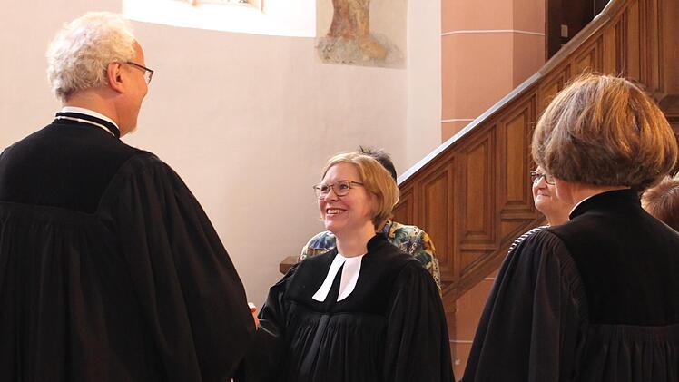 Dekan Hans-Martin Lechner übergibt Pfarrerin Kathrin Seeliger die Urkunde.   Foto: Evi Seeger