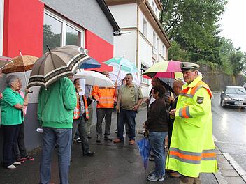 Die Anwohner aus Friedrichsburg besprachen am Donnerstag mit Behördenvertretern, wie der Unfallschwerpunkt entschärft werden kann. Derweil fuhren viele Autos und auch Laster an ihnen vorbei. Ursache für den Termin war der Lasterunfall vom 11. April, wo das Haus im Hintergrund stark beschädigt wurde.  Foto: Friedwald Schedel