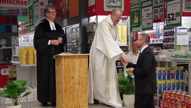Pfarrer Martin Gundermann und Domkapitular Thomas Teuchgräber (von links) übergaben  ein Kreuz an den Hagebau-Geschäftsführer Eric Bienlein-Karst. Foto: Heike Schülein