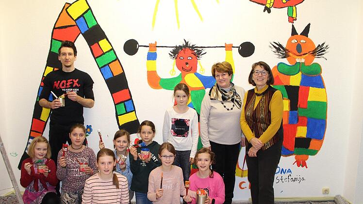 : Jan Marberg, Brigitte Meyerdierks und Claudia Körber (rechts) präsentieren zusammen mit Schülerinnen der Vierten Klassen die neue Wandbemalung in der Kinderbibliothek.