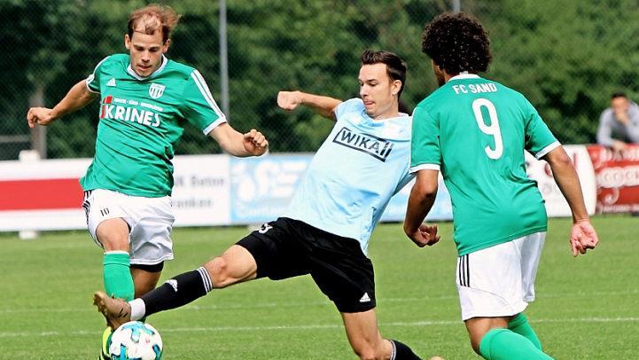 Im letzten Moment hält der Erlenbacher noch den Fuß in den Schuss des Sander Routiniers Sebastian Wagner (links) und lenkt den Ball ab; rechts lauert Tevin Mc Collough vom FCS, kann jedoch in dieser Situation nicht eingreifen. Fotos: Günther Geiling