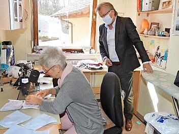 Bürgermeister Rainer Detsch schaut Gabi Weber bei der Herstellung der Nasen- und Mundmasken zum Schutz gegen das Coronavirus über die Schulter. Eine erste Maske probierte er vor Ort gleich aus. Foto: K.- H. Hofmann
