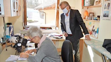 Bürgermeister Rainer Detsch schaut Gabi Weber bei der Herstellung der Nasen- und Mundmasken zum Schutz gegen das Coronavirus über die Schulter. Eine erste Maske probierte er vor Ort gleich aus. Foto: K.- H. Hofmann