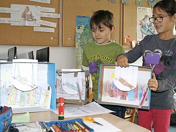 Julius und Antonia sind bereits fertig mit ihren "Wunderboxen" und zeigen bei geöffnetem Deckel, wie das Guckloch-Kino aufgebaut ist.  Foto: Sabine Weinbeer