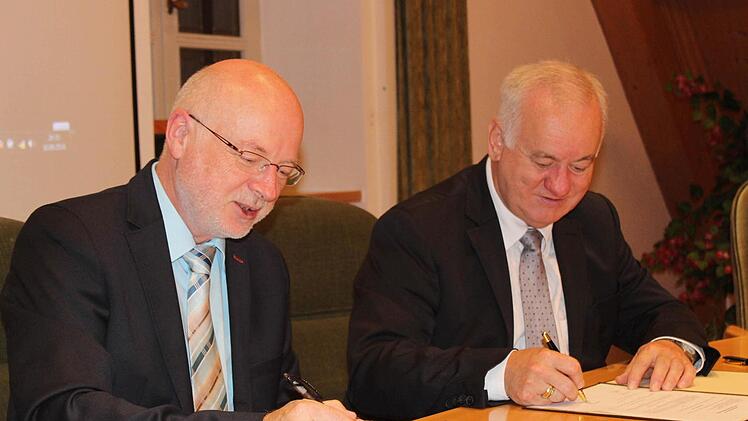 Igensdorfs Bürgermeister Wolfgang Rast (l.) und sein Weißenoher Amtskollege Rudolf Braun setzen ihre Unterschriften unter den Kooperationsvertrag in Sachen Breitbandausbau.  Fotos: fra-press