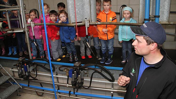 Landwirt Stefan Bramann (rechts) erklärt den Kindern den Melkstand.