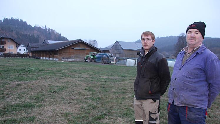 Johannes  (links) und Christian Nickel stehen dort, wo sie einen neuen Stall für ihre Milchkühe bauen wollen. Im Hintergrund: der bestehende Stall, in dem künftig ausschließlich die jungen Kälber aufgezogen werden sollen. Foto: Veronika Schadeck