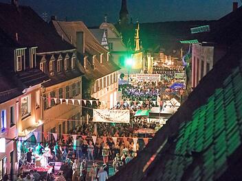 Ein gut besuchtes Straßenfest in Scheßlitz bei Nacht mit stimmungsvoller Beleuchtung, bunten Wimpeln und Live-Musik. Zahlreiche Menschen genießen die festliche Atmosphäre.
