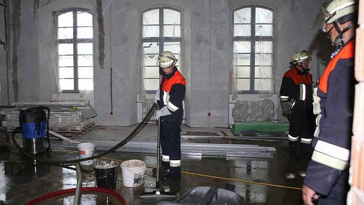 Feuerwehrleute saugen Löschwasser ab, das vom Dach in darunter liegende, schon weitgehend sanierte Räume gesickert ist.   Fotos: RiegerPress/Archiv
