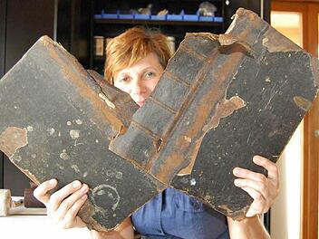 Restauratorin Sabine Schumm demonstriert, dass die Bibel in schlechtem Zustand war. Die Buchdeckel hingen nur noch an Fäden. Fotos: Andreas Welz