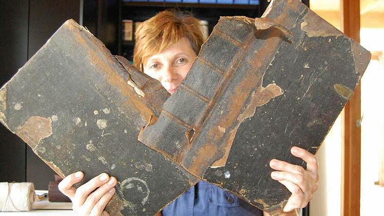 Restauratorin Sabine Schumm demonstriert, dass die Bibel in schlechtem Zustand war. Die Buchdeckel hingen nur noch an Fäden. Fotos: Andreas Welz