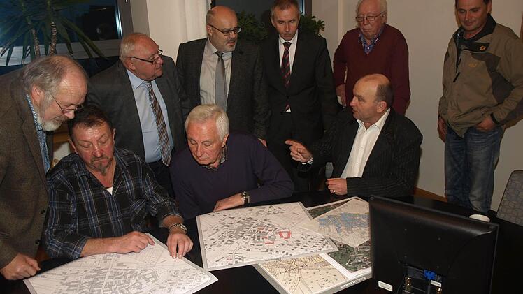 Vergleichen die Neufassung des Katasters mit früheren Planwerken: Die Feldgeschworenen Ludwig Hilpert (von links, sitzend) Fridolin Schubert und Manfred Greubel sowie (stehend, von links) Bernhard Simon vom Vermessungsamt, Altbürgermeister Siegfried Erhard, Bürgermeister Franz Kuhn, Konrad Unsleber (Leiter des Vermessungsamts Bad Kissingen) sowie die Feldgeschworenen Alfred Schubert und Günther Kuhn.  Foto: S. Geiger