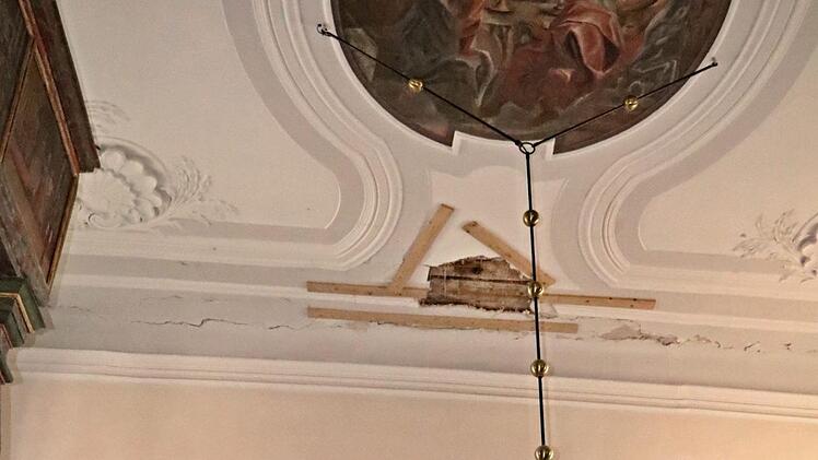 Pfarrerin Sonja von Aschen zeigt auf die Hauptschadstelle an der Decke über dem Altarraum. Risse sind daneben rundum in der gesamten Kirche erkennbar. Foto: Helmut Will