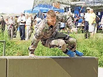 Ein französischer Reservist schwingt sich auf der Hindernisbahn über eine Mauer. Foto: Arkadius Guzy