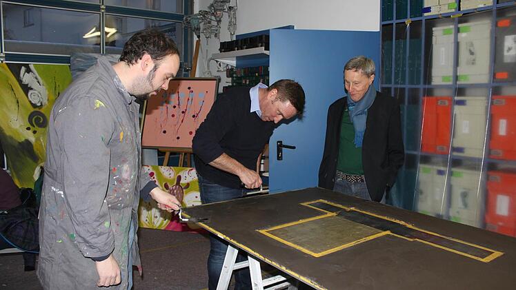 An einer Holzplatte wird in Schiefertechnik gearbeitet. Im Bild von links Sebastian Säum, Malermeister Martin Vogt und Ludwig Müller vom Rotary-Club Foto: Popp