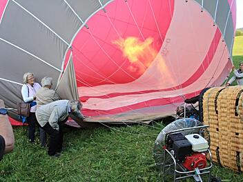 Der Ballon wird mit Heißluft gefüllt. Dabei helfen die Ballonfahrerinnen links und rechts des Brenners kräftig mit. Foto: Helmut Will