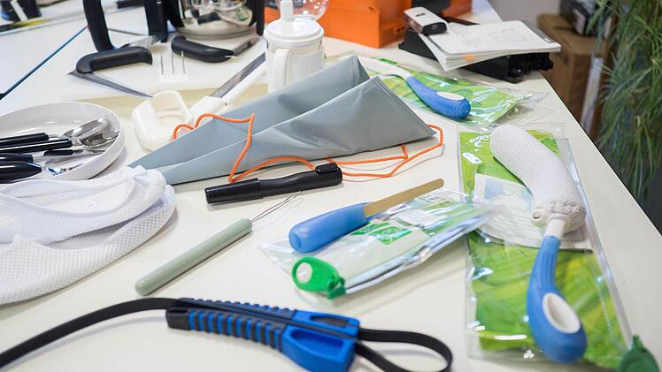 Weitere Hilfsmittel sind ein Dosenöffner, der über Hebelwirkung funktioniert (vorne), eine Waschhilfe (rechts) oder eine Strumpfanziehhilfe aus Nylon (Mitte). Foto: Marian Hamacher