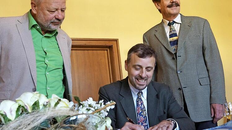 William E. Moeller (Mitte) trägt sich ins Goldene Buch ein.