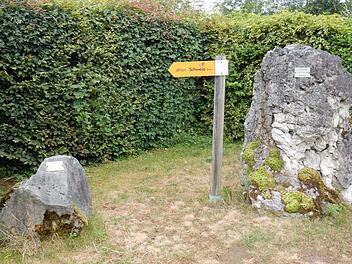 Die kleine Anlage, die heute noch vor dem Eingang zum Landratsamt Ebermannstadt zu finden ist, erinnert an die Steinübergabe von 1992. Der kleine Sandstein (l.) stammt aus dem Partnerlandkreis zu Forchheim, aus der Sächsischen Schweiz, der rechte größere aus dem Pölnitzer Forst; dazwischen steht der Wegweiser in die Schweiz mit Kilometerangabe. Foto: Reinhard Löwisch